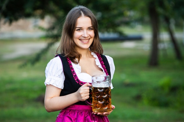 Foto de mooie brunette houdt 2 pintjes bier vast op het oktoberfest in duitsland.