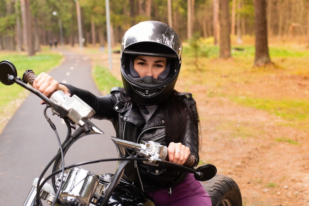 De mooie en gelukkige brunette op een motorfiets