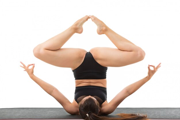 De mooie flexibele vrouw die yoga doet stelt op witte achtergrond