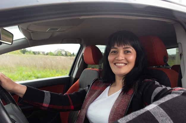 De mooie gelukkige vrouw in de auto