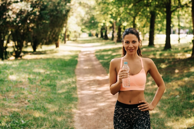 De mooie geschikte jonge vrouw drinkt water van een fles