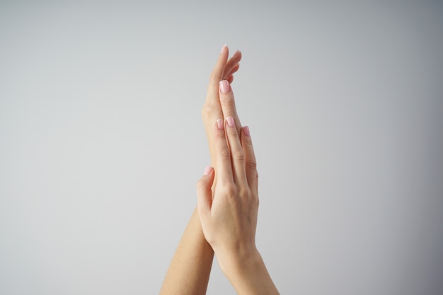 De mooie handen van een jong meisje met mooie manicure op een grijze vlakke achtergrond leggen. Spa en manicure concept.