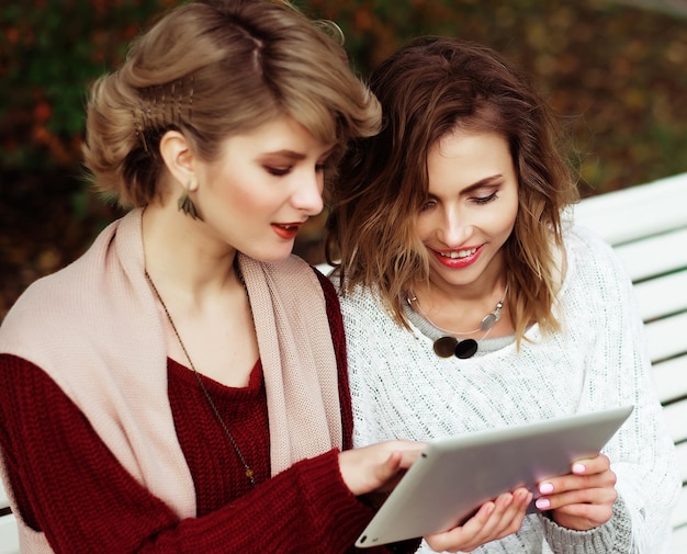 De mooie herfst die van vrouwenmeisjes tablet gebruiken openlucht