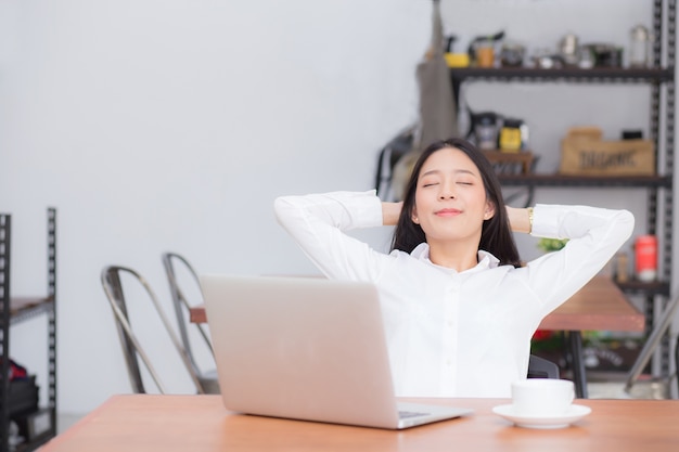 De mooie jonge Aziatische vrouw met laptop rek en de oefening ontspannen na het werksucces.