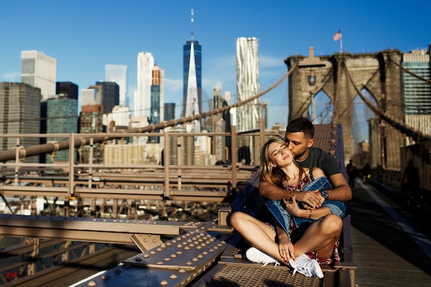 De mooie jonge man en de vrouw stellen op de brug van brooklyn in de stralen van ochtendzon