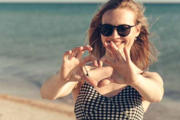 De mooie jonge vrouw geniet de zomer van vakantie op het strand