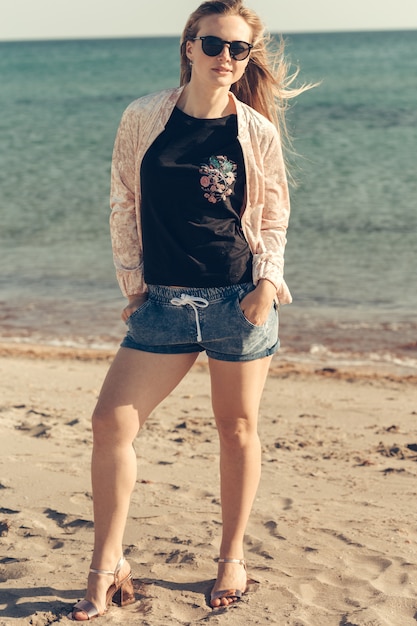 De mooie jonge vrouw geniet de zomer van vakantie op het strand