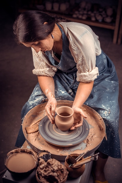 De mooie jonge vrouwenmeester toont het proces van het maken van ceramische schotels met behulp van de oude technologie. Handwerk.