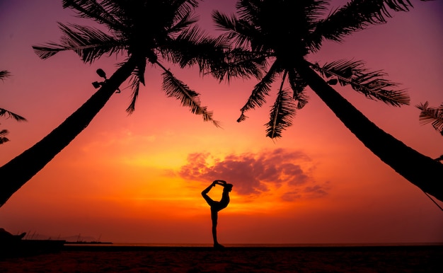 De mooie jonge yoga van vrouwenpraktijken bij het strand. Ochtendtraining. zonsopkomst