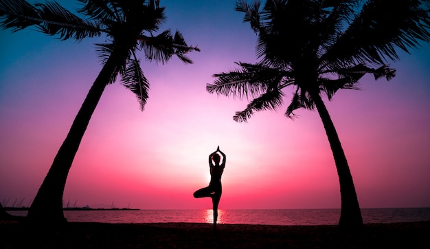 De mooie jonge yoga van vrouwenpraktijken bij het strand. Ochtendtraining