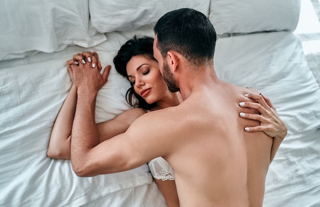 De mooie man en vrouw in ondergoed hebben seks in bed Premium Foto afbeelding