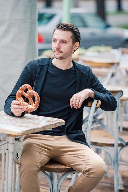 De mooie pretzel van de jonge mensenholding en het ontspannen in park