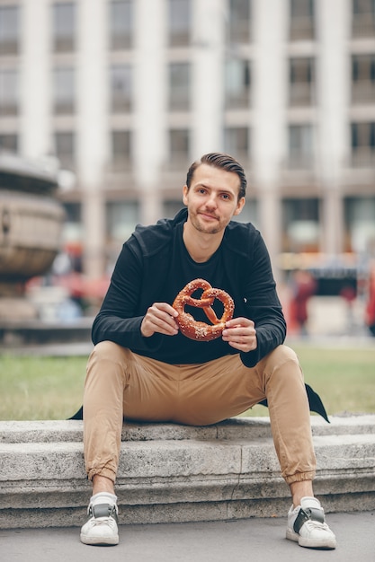 De mooie pretzel van de jonge mensenholding en het ontspannen in park