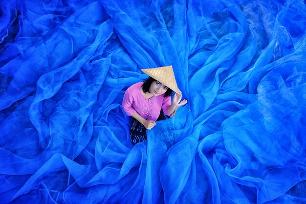 De mooie Thaise vrouw oogst indigo op blauwe netto vloer