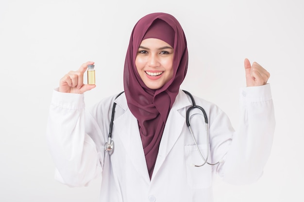 De mooie vrouw arts met hijab houdt vaccin op witte achtergrond