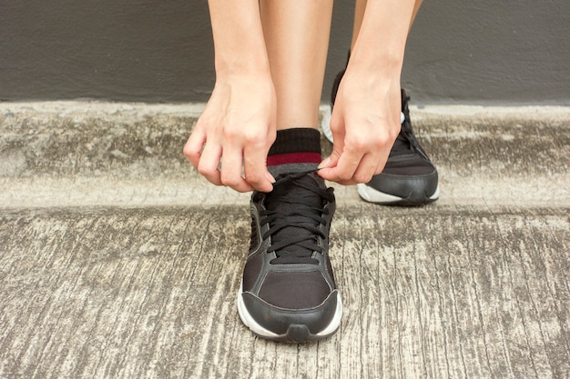 De mooie vrouw bindt haar schoenen vast