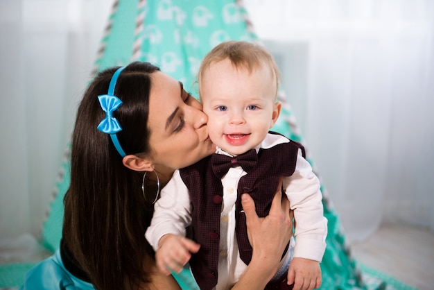 De mooie vrouw en haar kleine zoon spelen en glimlachen, op blauwe achtergrond.