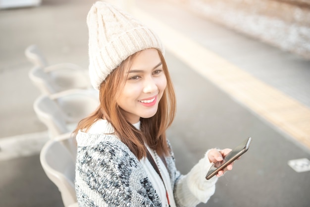 De mooie vrouw gebruikt slimme telefoon op spoorwegplatform