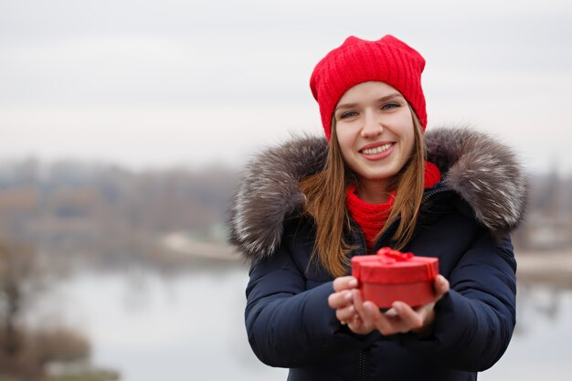 De mooie vrouw houdt een doos met een gift in haar handen