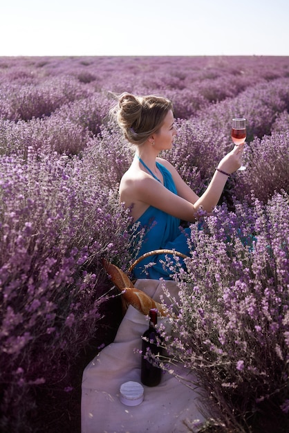 De mooie vrouw houdt een glas roze wijn. Meisje ontspannen op picknick met kaas camembert, Frans stokbrood en wijn