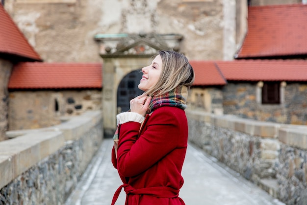 De mooie vrouw in rode laag blijft dichtbij kasteel