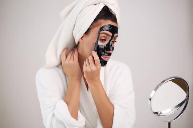 De mooie vrouw verwijdert een reinigingsmasker van haar gezicht