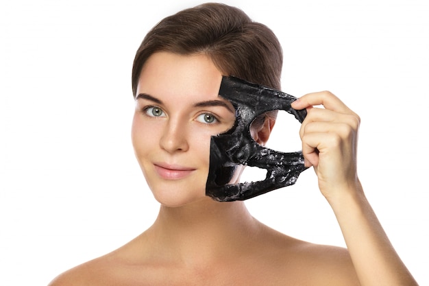 De mooie vrouw verwijdert zuiverend masker uit haar gezicht