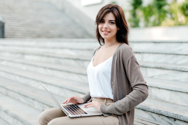 De mooie vrouw werkt in openlucht op laptop