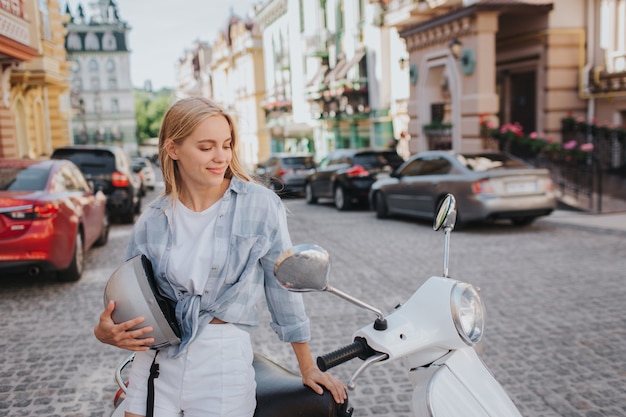 De mooie vrouw zit op motorfiets en bekijkt het