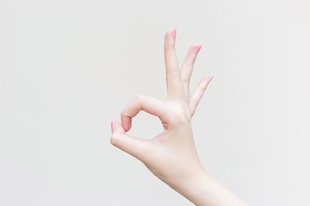 De mooie vrouwelijke hand toont vingersymbool als OK teken in manicureconcept.