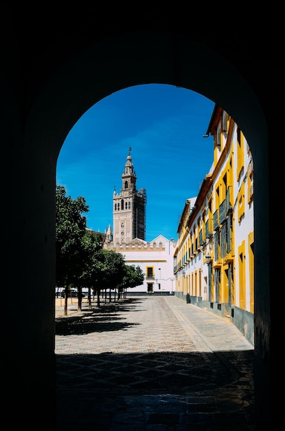 De Moorse Giralda-toren van de kathedraal van Sevilla zoals ingelijst vanuit een deuropening op de binnenplaats in Real Alcazar Sevilla Andalusië Spanje