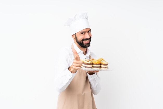 De muffincake van de jonge mensenholding over geïsoleerd het richten aan de voorzijde en het glimlachen