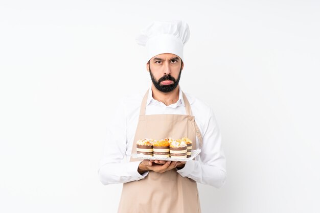 De muffincake van de jonge mensenholding over geïsoleerd met droevige en depressieve uitdrukking