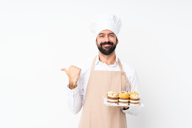 De muffincake van de jonge mensenholding over geïsoleerd wit die aan de kant richten om een product voor te stellen