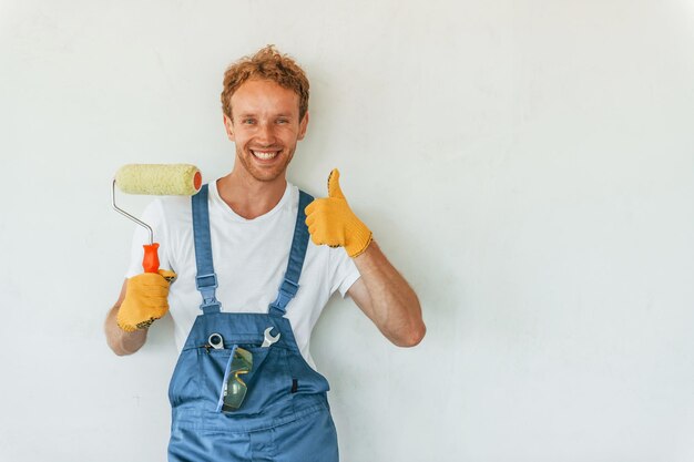 De muren schilderen Jonge man die overdag in uniform aan het werk is