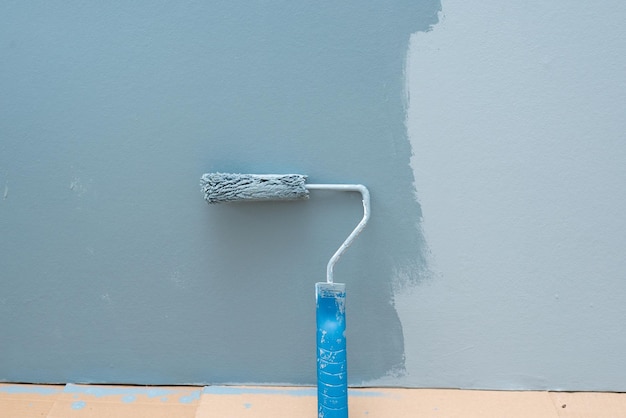 Foto de muur schilderen met een rol in blauwe kleur