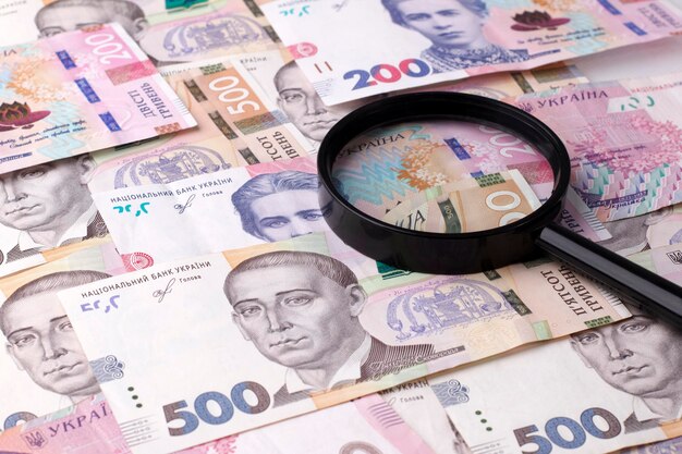 De nationale munteenheid van Oekraïne is de hryvnia. Financiële achtergrond met 200 en 500 hryvnia rekeningen en een vergrootglas. Oekraïens geld.