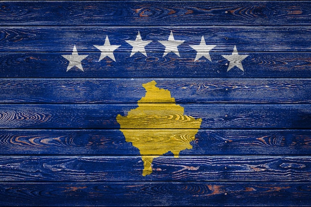 De nationale vlag van Kosovo is geschilderd op een kamp van even planken die met een spijker zijn genageld. Het symbool van het land.