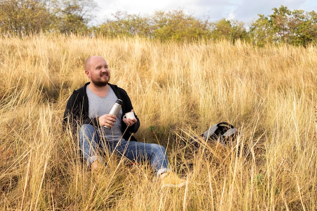 De natuur, een man die op het gras rust met thee