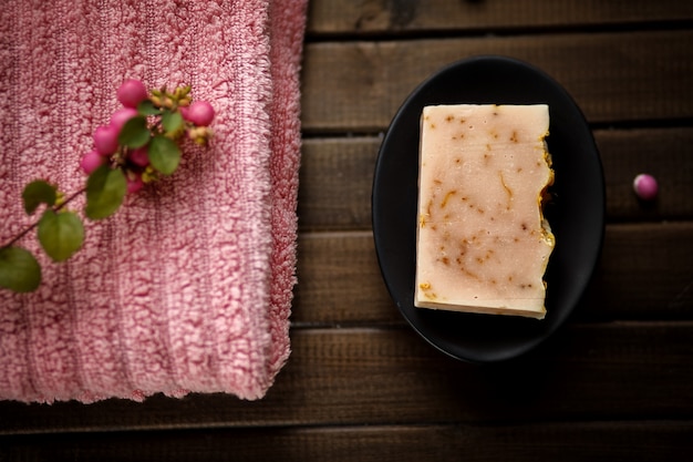 Foto de natuurlijke zeep en een roze handdoek tegen bruine houten vlakke achtergrond, hoogste mening, leggen, organisch schoonheidsmiddelenconcept