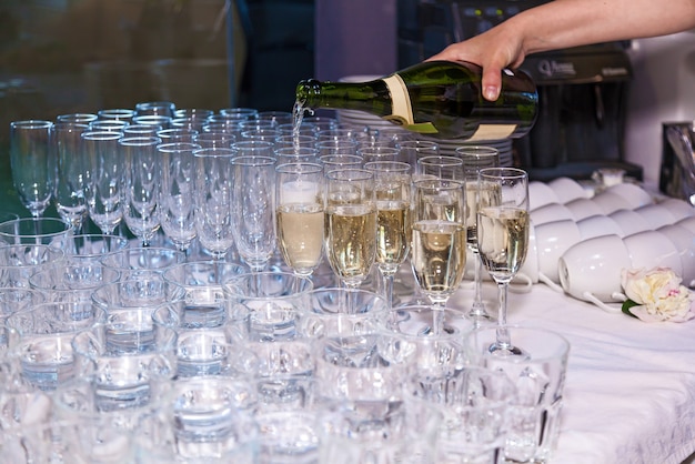 De ober giet champagne in glazen uit een fles in een restaurant. Catering, banket