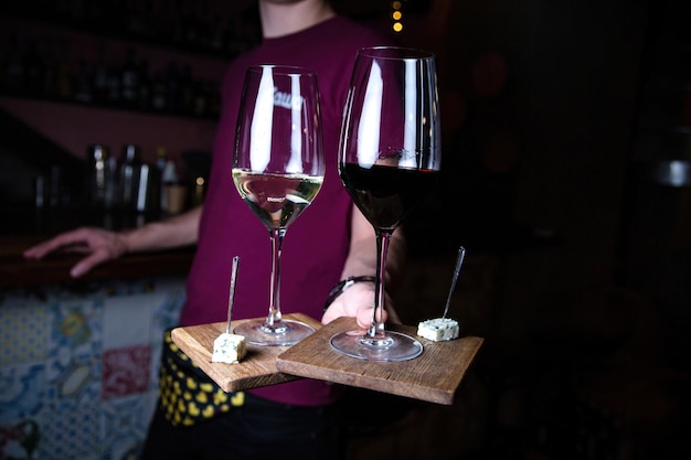 De ober houdt twee glazen wijn vast. Rode en witte wijn