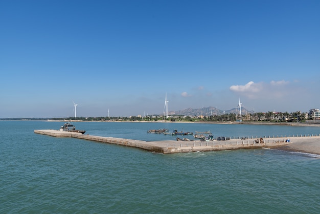 De oceaan onder de blauwe lucht, het schip dat aan de kade ligt of de zee