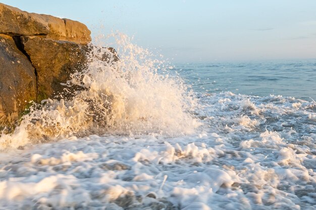 De oceaankust wordt gewassen door een golf. Spatten van water. Zandkust bij zonsondergang