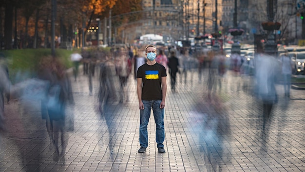 De Oekraïense man met medisch gezichtsmasker staat op de drukke straat