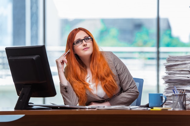 De onderneemsterzitting van de roodharige bij haar bureau in het bureau