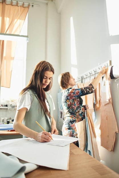 De ontwerper tekent met een potlood op papier schetsen van kleding