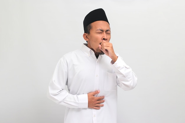 Foto de onwel jonge indonesische man hoest en lijdt aan hoest en griep geïsoleerd op een witte achtergrond