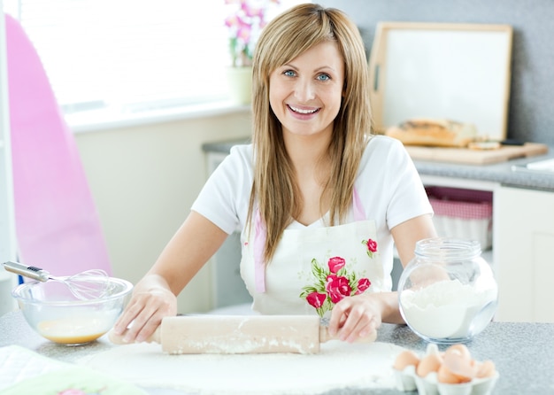 De opgetogen vrouw bereidt een cake in de keuken voor