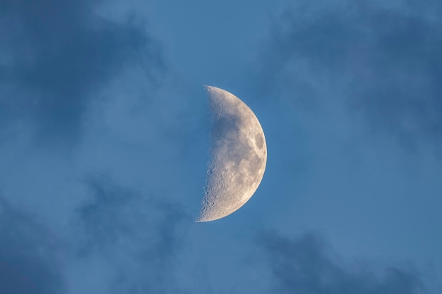 Foto de opkomende maan op een zachte blauwe hemel met lichte wolken